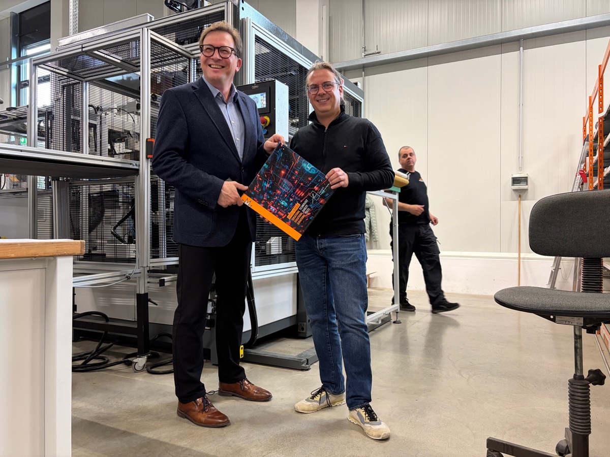 Franc Dierl, MdL und Andreas Hertel, Gesch�ftsleitung vor einer der neuesten Errungenschaften im Maschinenpark:  Die �berzugsanlage, eine hochpr�zise und effektive Maschine, die diverse Kartonagenformen und -gr��en foliert.